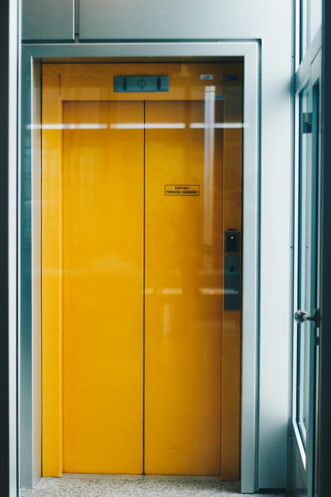 A bold yellow elevator door captured indoors, offering a bright contrast in modern architecture.