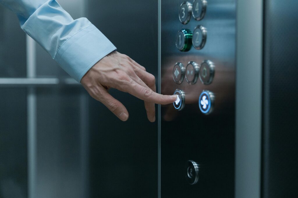 A person pressing an elevator button in a modern building, highlighting technology and urban life.